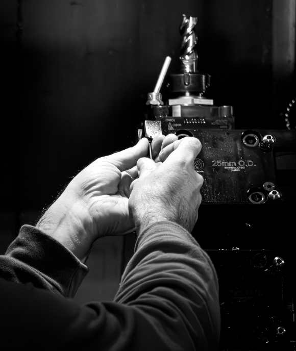 Hands operating CNC lathe on Nimbus suspension components